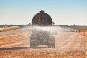 Agricultural truck irrigating a wheat field with a water tank